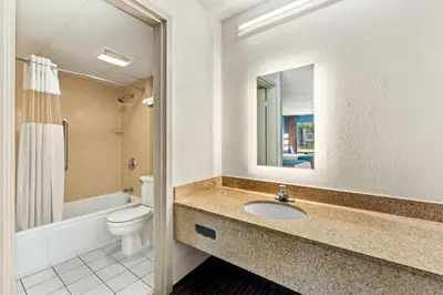 a bathroom with a sink and a toilet and a mirror at Howard Johnson by Wyndham Albany in Albany