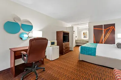 a hotel room with a bed and a desk and a chair at Howard Johnson by Wyndham Albany in Albany