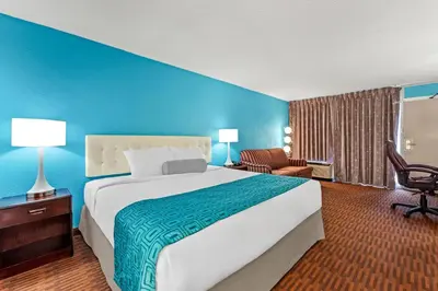 a large bed in a hotel room with a blue wall at Howard Johnson by Wyndham Albany in Albany