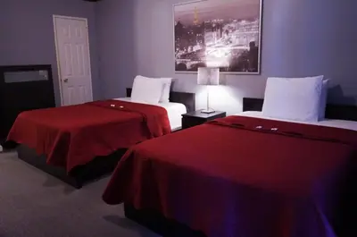 a hotel room with two beds with red sheets at Central Motel Courtyard in White Plains