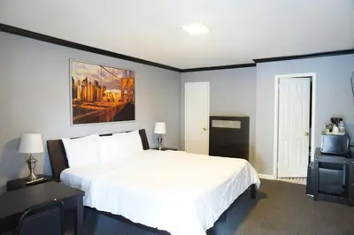 a bedroom with a white bed and a painting on the wall at Central Motel Courtyard in White Plains