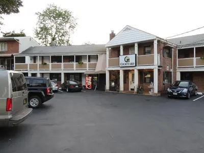 a parking lot with cars parked in front of a building at Central Motel Courtyard in White Plains