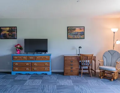 a living room with a television and a chair and a dresser at Allen Lake Resort Richfield Springs Cooperstown in Richfield Springs