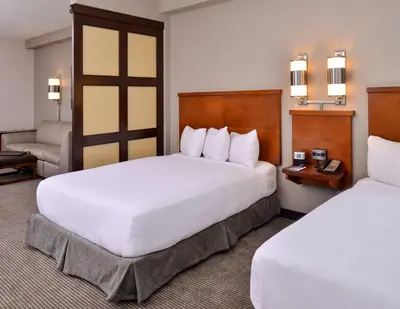 a hotel room with two beds and a chair at Hyatt Place Garden City in Garden City