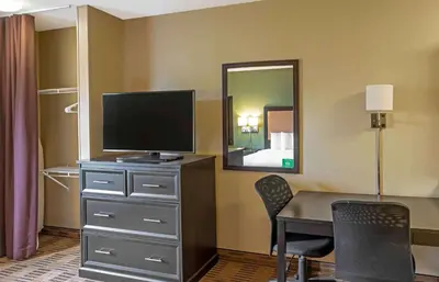 a room with a desk with a television and a bedroom at Extended Stay America Suites - Meadowlands - Rutherford in Rutherford