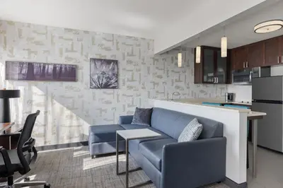 a living room with a blue couch and a kitchen at Residence Inn by Marriott The Bronx at Metro Center Atrium in Bronx