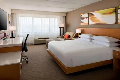 a hotel room with a large bed and a desk at Delta Hotels by Marriott Utica in Utica