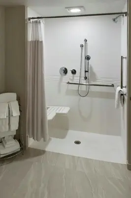 a white bathroom with a shower and a tub at Delta Hotels by Marriott Utica in Utica