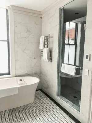 a bathroom with a tub and a sink and a mirror at The Adelphi Hotel in Saratoga Springs