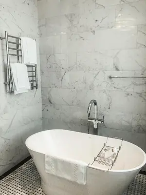 a white bath tub in a bathroom with marble walls at The Adelphi Hotel in Saratoga Springs