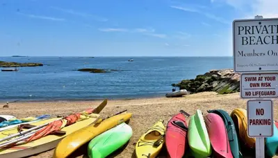 a bunch of surfboards on a beach next to the water at Cozy Garden Apartment Along the Shoreline in Guilford