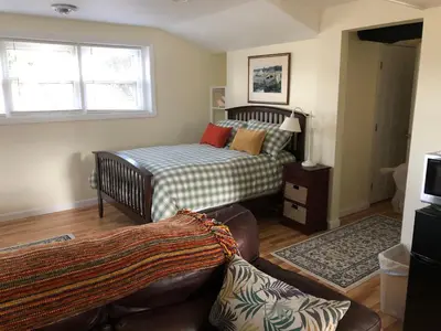a bedroom with a bed and a couch in a room at Cozy Garden Apartment Along the Shoreline in Guilford