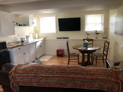 a living room with a table and a kitchen at Cozy Garden Apartment Along the Shoreline in Guilford