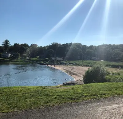 a rainbow in the sky over a pond with trees at Cozy Garden Apartment Along the Shoreline in Guilford