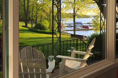 two chairs on a porch with a view of the water at Silver Birches Resort in Hawley