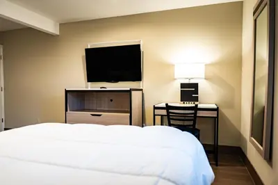a bedroom with a bed and a desk with a television at Whitman Motor Lodge in Huntington