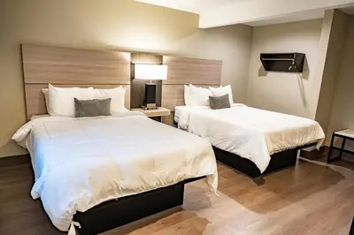 a hotel room with two beds with white sheets at Whitman Motor Lodge in Huntington