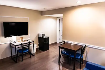 a room with a table and chairs and a television at Whitman Motor Lodge in Huntington
