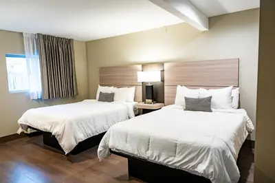 a hotel room with two beds with white sheets at Whitman Motor Lodge in Huntington