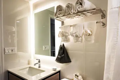a bathroom with a sink and a mirror and towels at Whitman Motor Lodge in Huntington