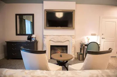 a living room with a fireplace and a table and chairs at Mirbeau Inn & Spa, Rhinebeck in Rhinebeck