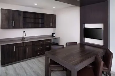 a kitchen with a wooden table and a tv at Hyatt Place Poughkeepsie - Hudson Valley in Poughkeepsie