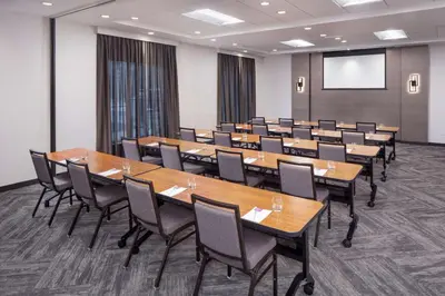 a conference room with tables and chairs and a screen at Hyatt Place Poughkeepsie - Hudson Valley in Poughkeepsie