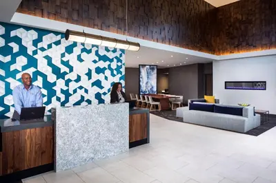 a lobby with a man and a woman sitting at a counter at Hyatt Place Poughkeepsie - Hudson Valley in Poughkeepsie