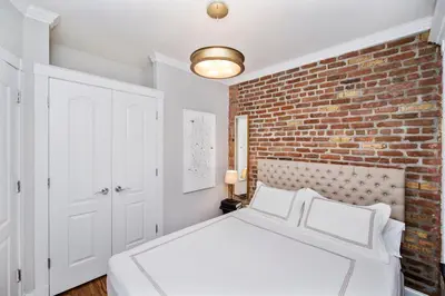 a bedroom with a white bed and a brick wall at APARTMENT NOLITA in New York