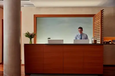 a man standing at a reception desk with a laptop at The Study at Yale, Study Hotels in New Haven