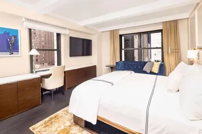 a hotel room with a bed and a desk and a television at Hilton Club The Quin New York in New York