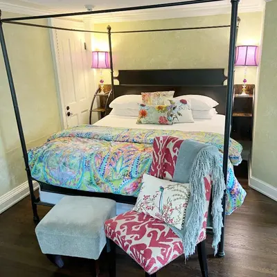 a bedroom with a canopy bed and a chair at The Connecticut River Valley Inn Hartford South/Glastonbury in Glastonbury