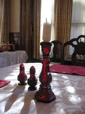a candle on a table with two dolls on it at Olde Judge Mansion B&B in Troy