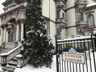 a sign in front of a building with a christmas tree at Batcheller Mansion Inn in Saratoga Springs