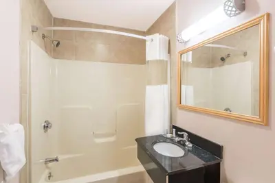 a bathroom with a sink and a shower and a mirror at Howard Johnson by Wyndham Springfield in Springfield