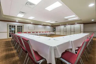 a conference room with a long table and red chairs at Howard Johnson by Wyndham Springfield in Springfield