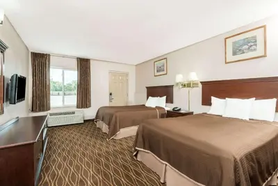 a hotel room with two beds and a flat screen tv at Howard Johnson by Wyndham Springfield in Springfield