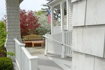 a white porch with a bench and an american flag at The Springwater Bed and Breakfast in Saratoga Springs