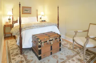 a bedroom with a bed with a trunk next to a chair at The Springwater Bed and Breakfast in Saratoga Springs