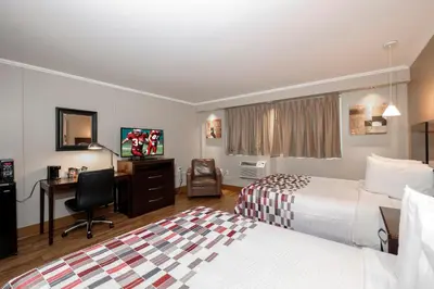a hotel room with two beds and a desk at Red Roof Inn and Suites Herkimer in Herkimer