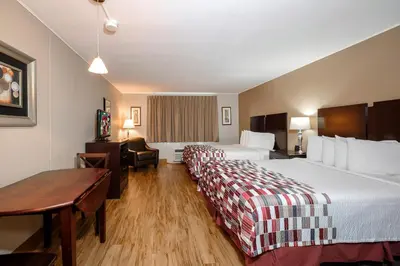 a hotel room with two beds and a desk at Red Roof Inn and Suites Herkimer in Herkimer