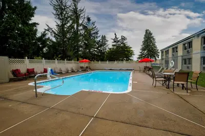 a swimming pool with chairs and a table and a building at Red Roof Inn and Suites Herkimer in Herkimer