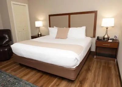 a bedroom with a large bed with white sheets and two lamps at D. Hotel Suites & Spa in Holyoke