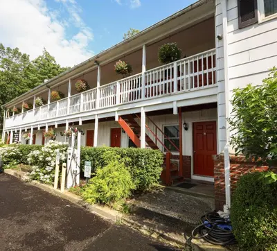 a white building with a porch with flowers on it at Chatham Travel Lodge in Old Chatham