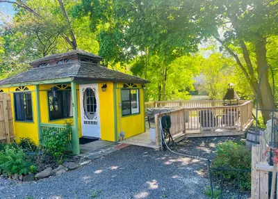 a small yellow house with a wooden deck at Micosta Leisure Inn in Hudson