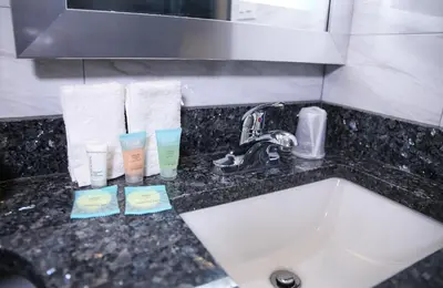 a bathroom counter with a sink and towels and a mirror at 7 Days Hotel in Bronx