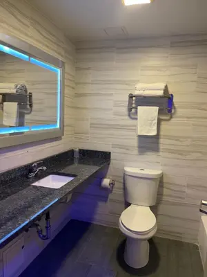 a bathroom with a toilet and a sink and a mirror at 7 Days Hotel in Bronx