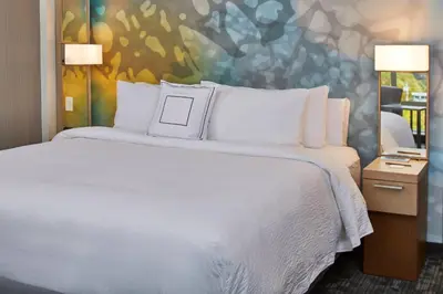 a bedroom with a large bed with white pillows at Courtyard by Marriott Albany Airport in Albany