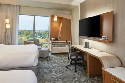 a hotel room with a desk and a television at Courtyard by Marriott Albany Airport in Albany