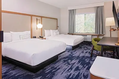 a hotel room with two beds and a desk at Fairfield Inn & Suites by Marriott Queensbury Glens Falls/Lake George in Queensbury